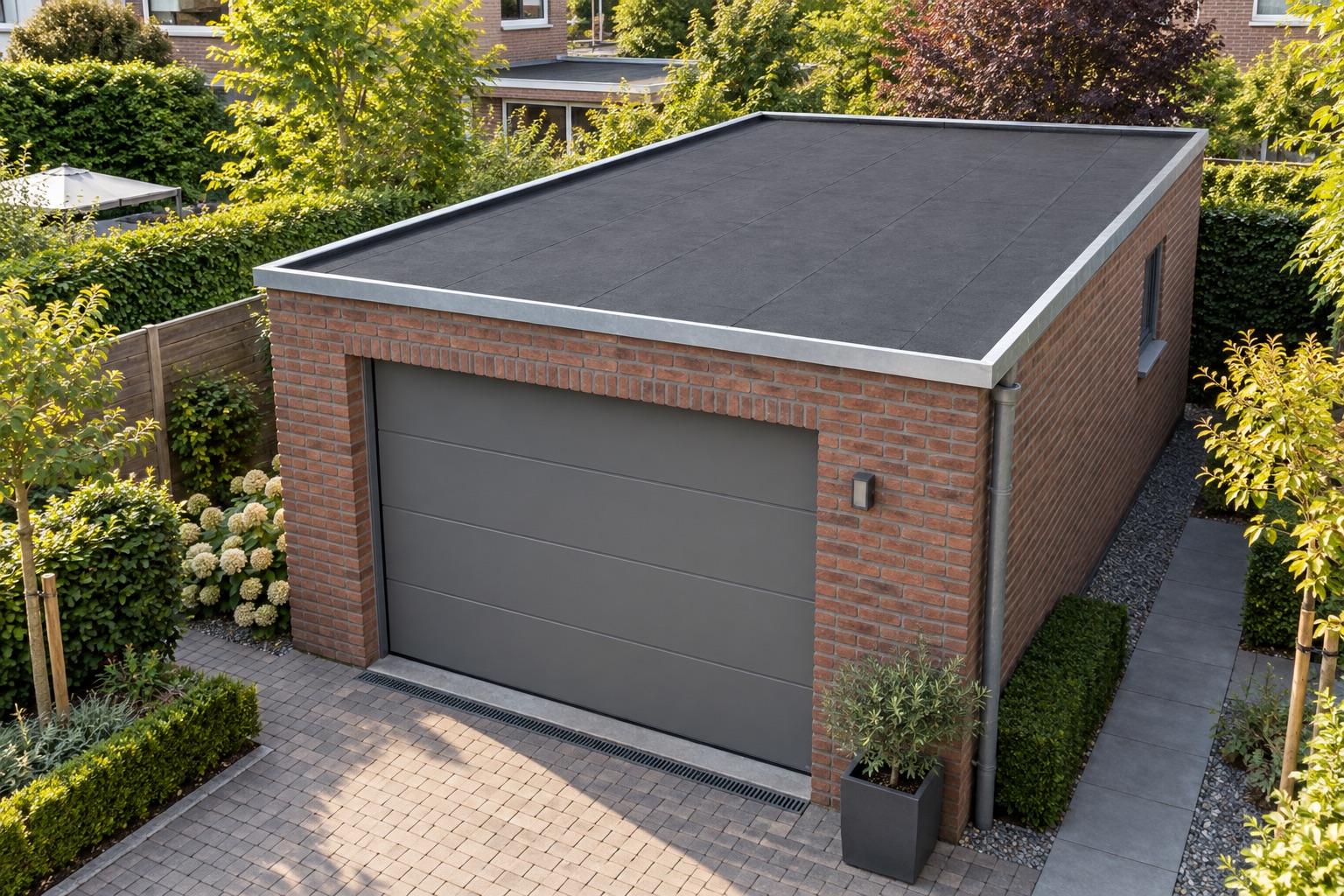 Vrijstaande garage met een zwart plat dak en brede garagedeur